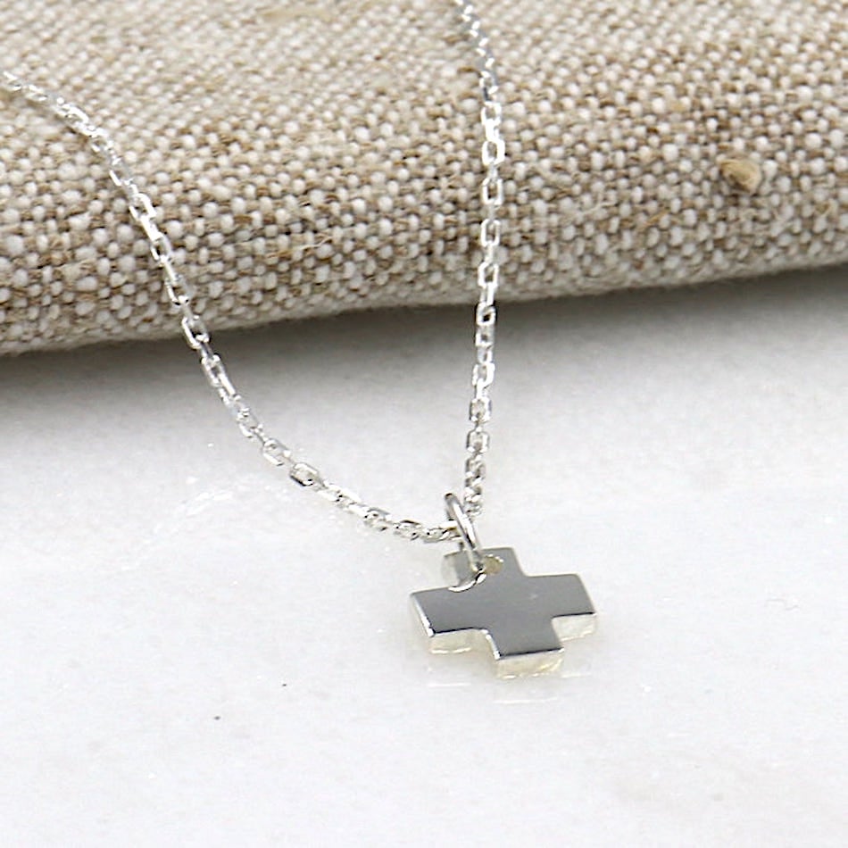 on peut voir un collier monté avec une croix et une chaine en argent pour femme