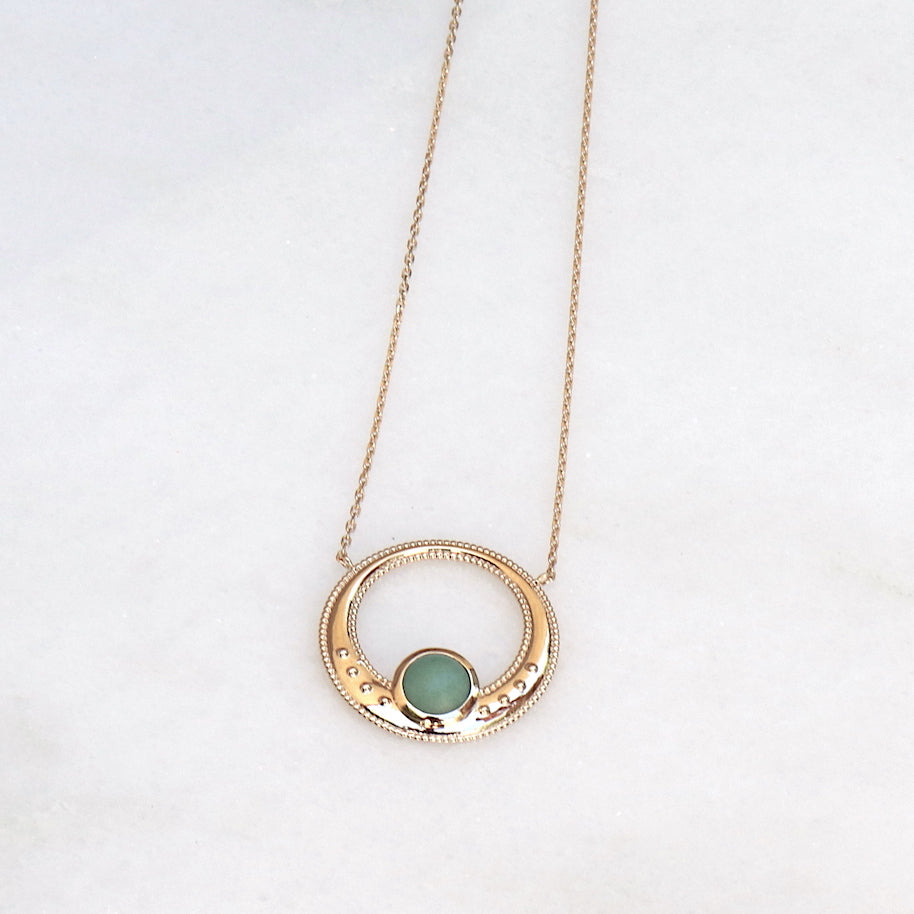 il y a un collier anneau en plaqué or pour femme associé à une pierre de gemmes ronde semi précieuse aventurine