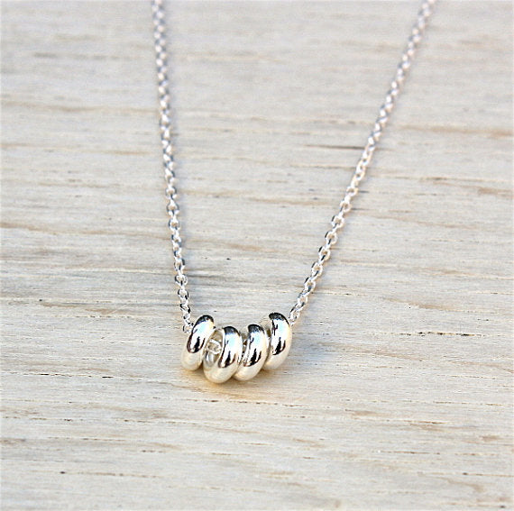 donuts en argent 925 monté sur une chaine pour ce collier femme présenté sur une planche de bois blanchi