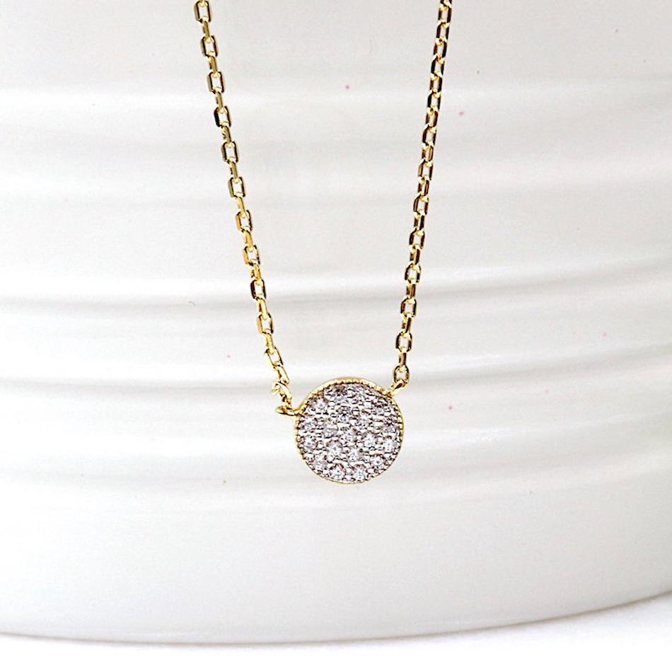 il y a un collier pour femme en plaqué or associé à une pastille recouverte de mini zircons