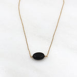 il y a un collier pour femme en plaqué or avec une pierre agate noire ovale