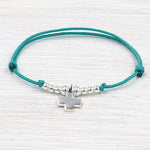 bracelet fait avec un cordon associé à une croix et des perles en argent 925