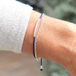 on peut voir un bracelet femme réalisé avec un cordon couleur personnalisable associé à une chaine forme rollot avec un jonc en argent 925 présenté sur un poignet