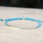 il y a un bracelet cordon couleur personnalisable associé à un jonc en argent 925 et des perles