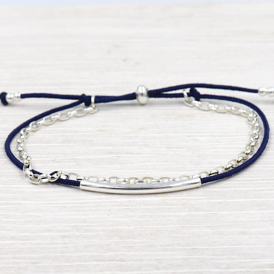 il y a un bracelet en argent 925 pour femme constitué d'un jonc, d'une chaine en argent 925 et un cordon haut de gamme couleur au choix présenté sur une planche en bois blanchi