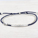 il y a un bracelet en argent 925 pour femme constitué d'un jonc, d'une chaine en argent 925 et un cordon haut de gamme couleur au choix présenté sur une planche en bois blanchi