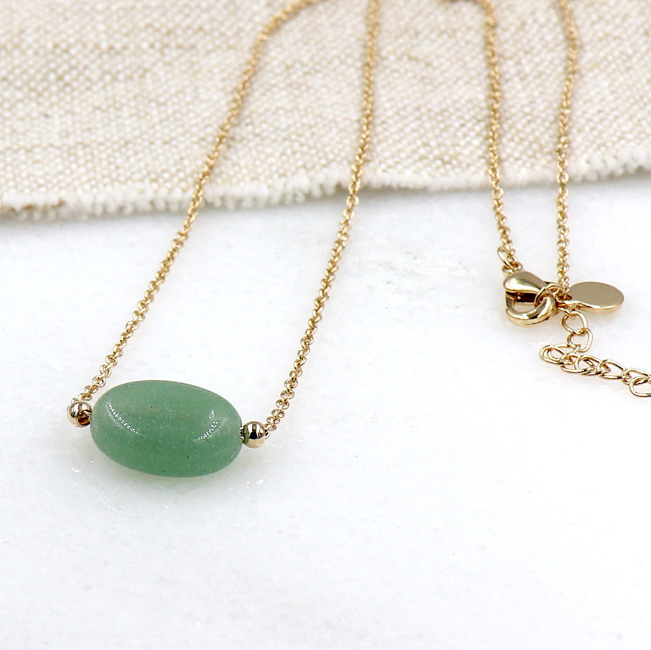 il y a un collier avec une pierre de gemmes aventurine ovale  montée sur une chaine en plaquée or