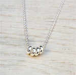donuts en argent 925 monté sur une chaine pour ce collier femme présenté sur une planche de bois blanchi