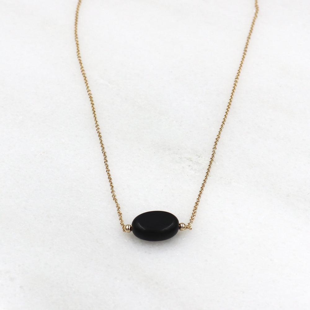 il y a un collier pour femme en plaqué or avec une pierre agate noire ovale